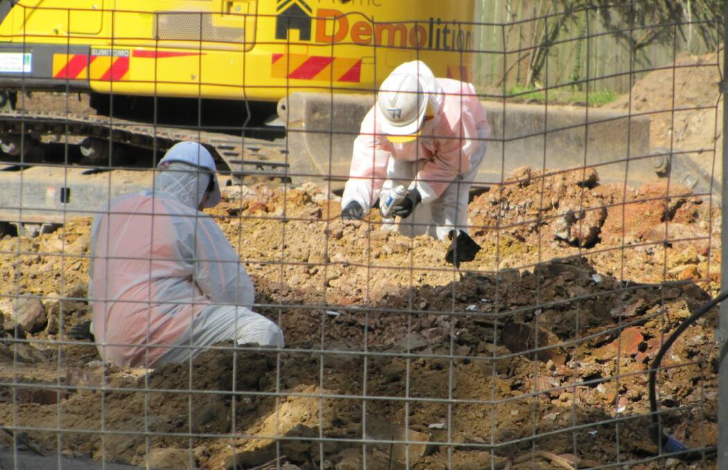 Workers in protective suits sift through material on the site. Picture: supplied