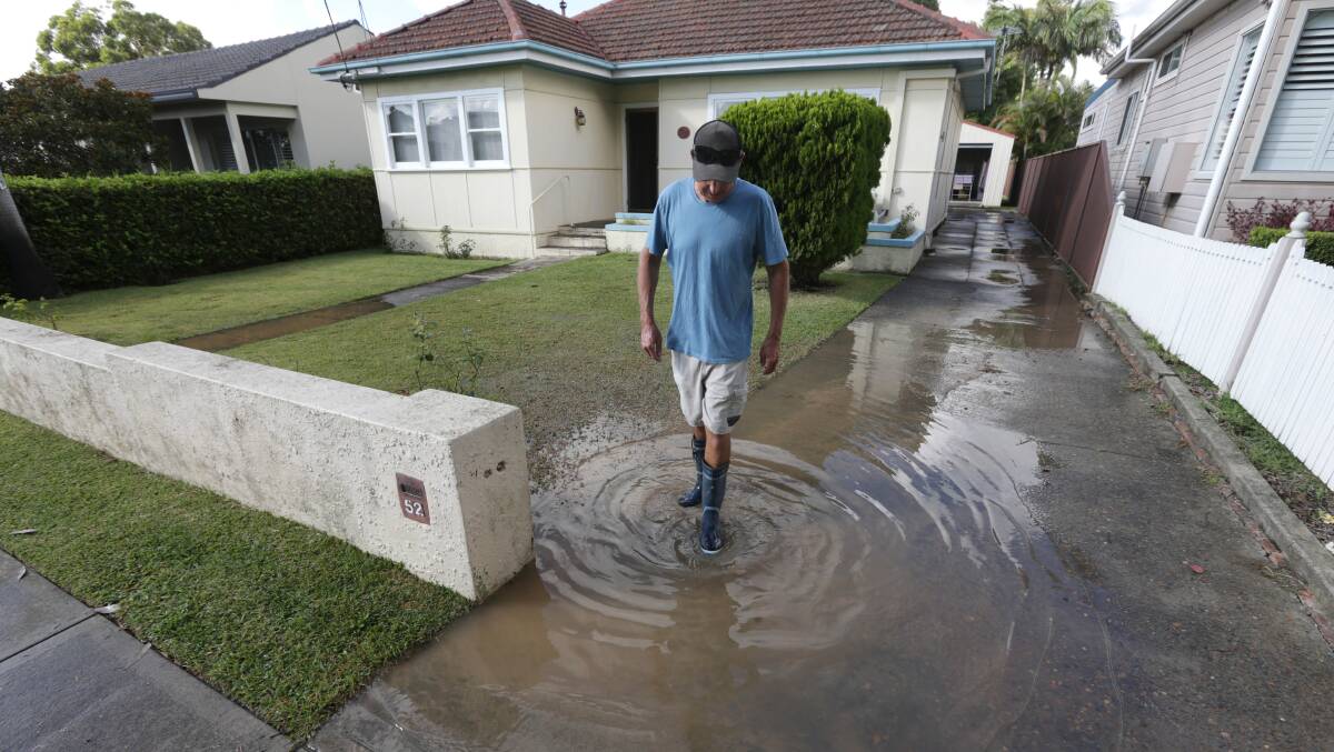 Waste water: Dale Badger wades through effluent outside his home last week. Picture: John Veage