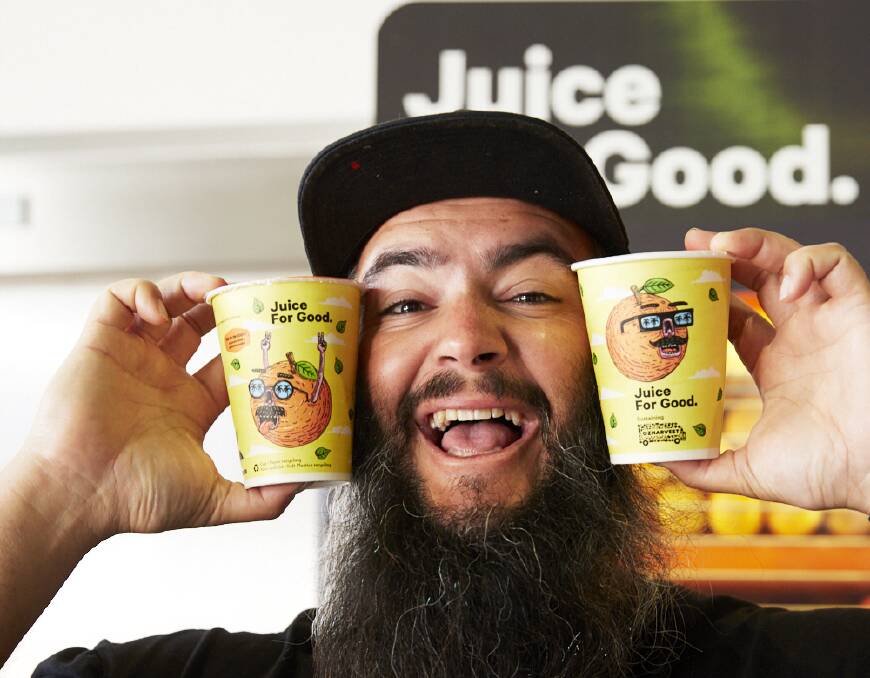 Freshly squeezed: Joel Moore 'aka Mulga' and the new Juice For Good cups which carry his artwork. Picture: Supplied