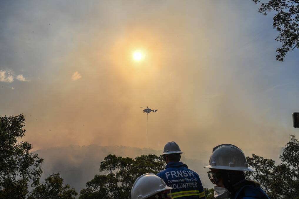 Water bombers tackle the bushfire in Alfords Point as fire crews watch and wait.. Picture: AAP