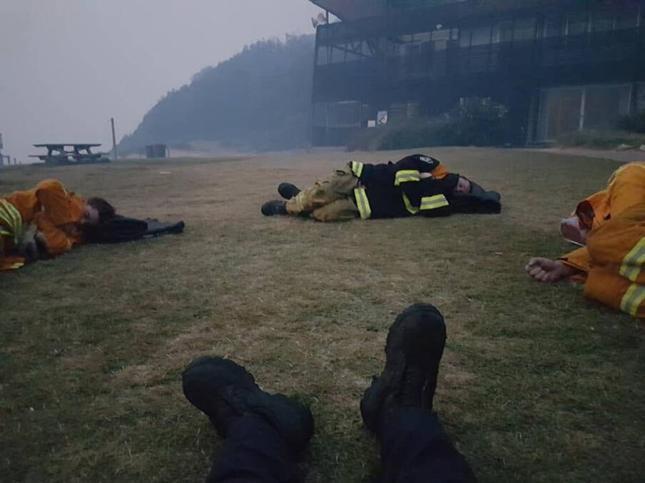 Awesome job: Exhausted firefighters resting at Garie Beach after helping to contain the Royal National Park fire. Picture: Edwina Illman