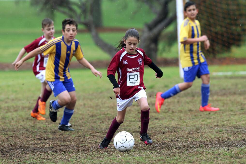 Skill: Carss Park FC 10B's player Tayla Cvetkovski tackles Arncliffe Aurora at Charles Pirie Field on Saturday. Teammate Ethan Massiuridis (maroon shirt) is in support. Picture: Jane Dyson
