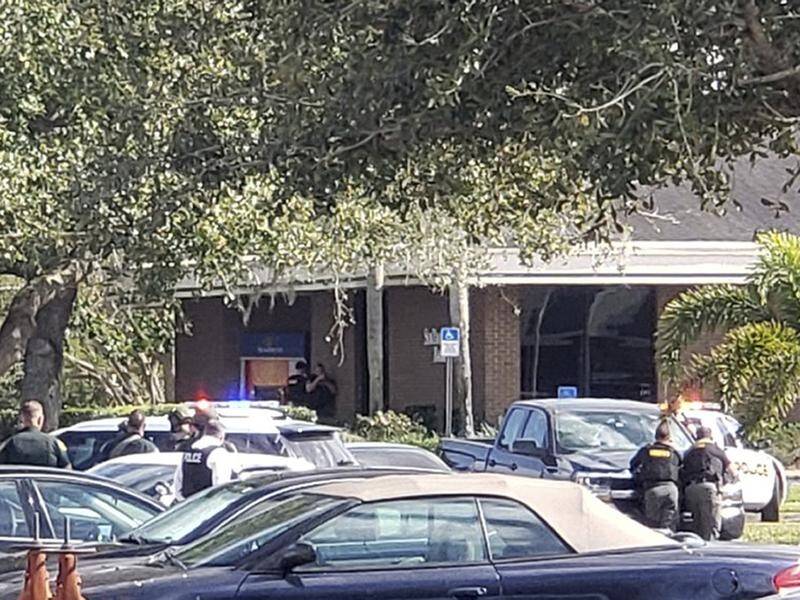 Police take cover outside a Florida bank after a shooting that killed five people.
