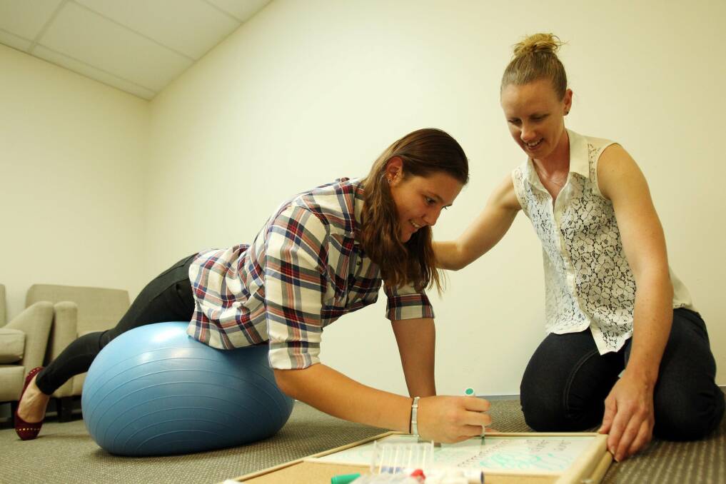 Getting a grip: Occupational therapist Jacky Peile teaches year 12 student Lauren Mowell ways to improve her handwriting. Picture: Chris Lane
