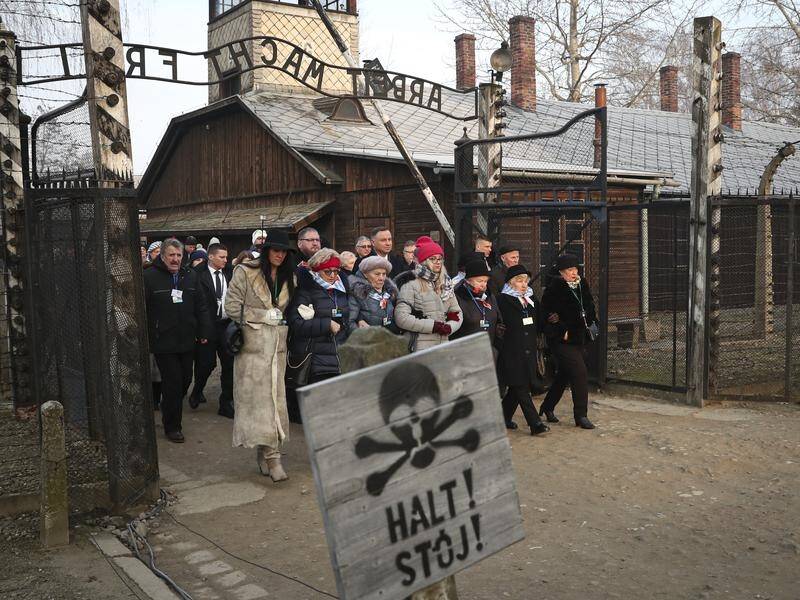 Polish President Andrzej Duda walks with survivors into the Auschwitz concentration camp.