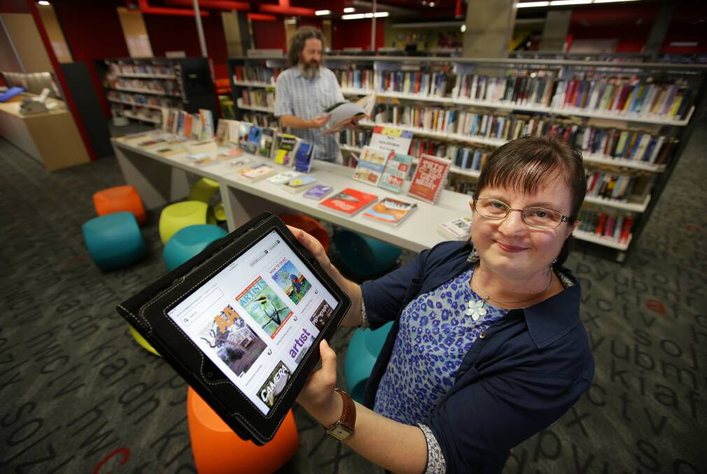 Popular pastime: Cronulla Library assistant Lisa Barnfield (above) shows how easy it is to download a book from the digital collection. Picture John Veage