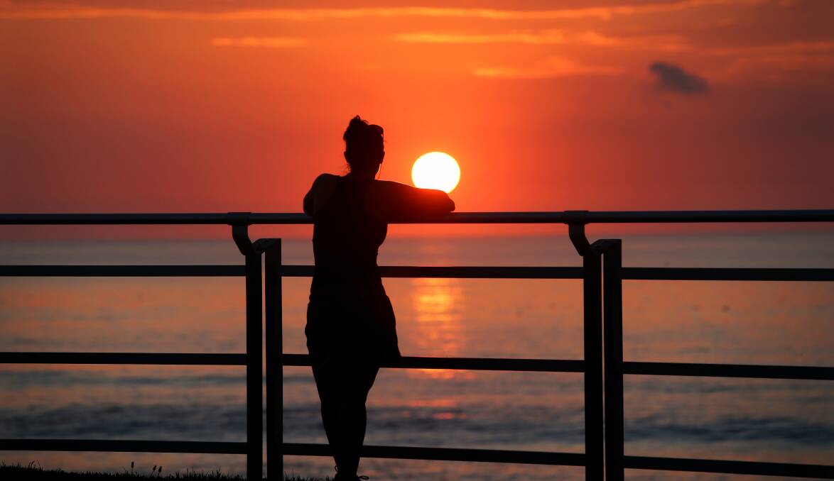 Walkers on the Cronulla esplanade stop to enjoy the sunrise over north Cronulla beach.Picture: John Veage
