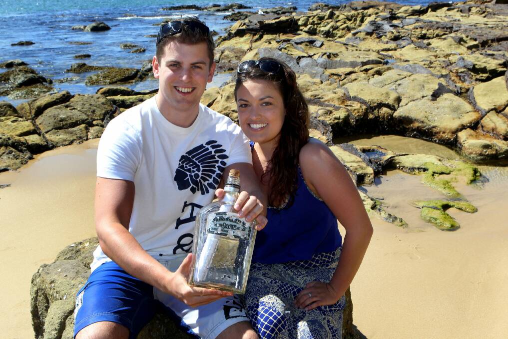 Jersey shore: British tourist Phil Ashley and his Aussie girlfriend Emma Topham with the bottle that was dropped into the ocean by two young brothers from outback NSW. Pictures: Lisa McMahon