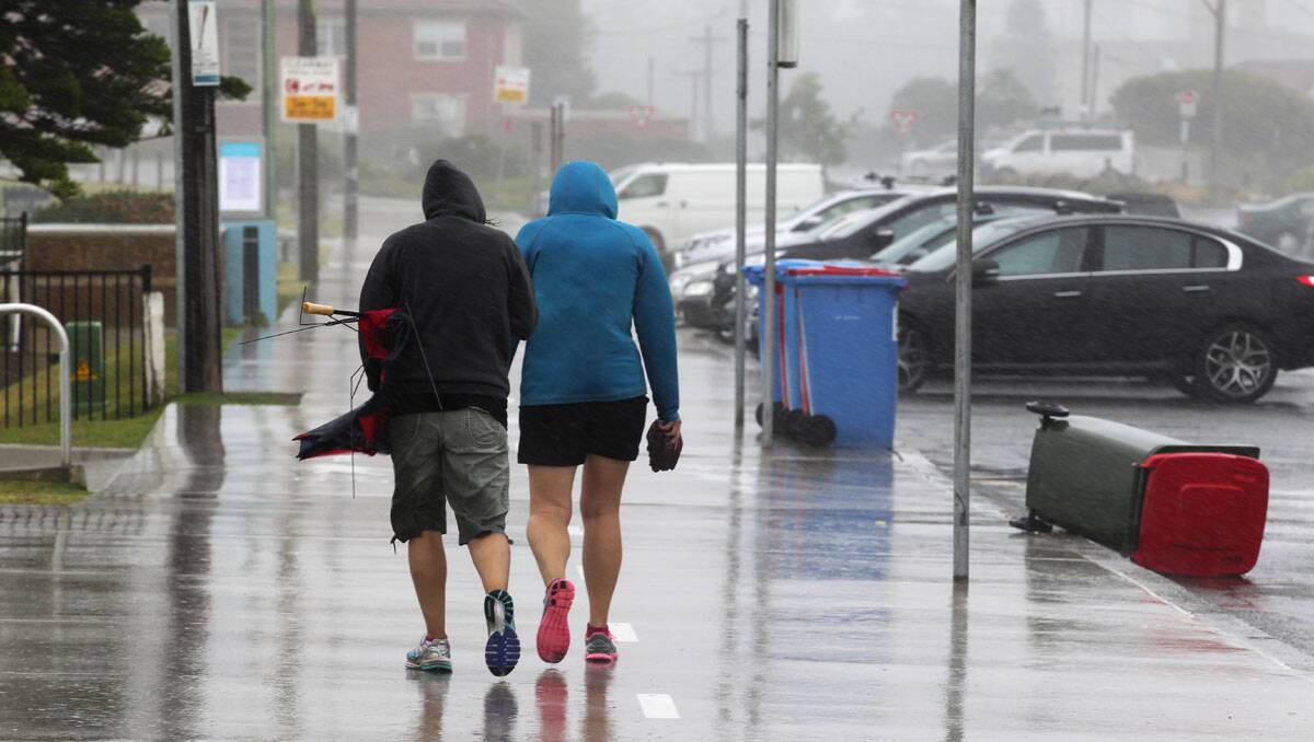 Walk whether the weather is good or bad: Two hardy souls brave cold, wet, windy conditions at Cronulla Monday. Picture: John Veage